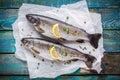 Two raw trouts on paper with thyme and lemon slices