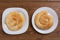 Two ready-made golden sweet cakes, lie on white plates, on a wooden table