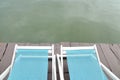 Two Recline chairs on dock facing a green lake.