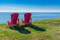 Two red adirondack chairs along the coast of Newfoundland Royalty Free Stock Photo