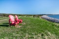 Two red adirondack chairs along the coast of Newfoundland Royalty Free Stock Photo