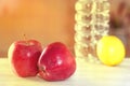 Two red apples on a white table, next to a bottle of water