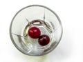 Two red berries of a cherry on the bottom of an empty glass cup, top view Royalty Free Stock Photo