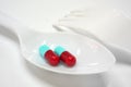 Two red and blue capsules on plastic spoon fork Royalty Free Stock Photo