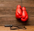 Two red boxing gloves hung on a wooden brown background, jump rope