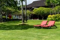 Two red chairs on a green lawn in a hotel somewhere in Nusa Dua, Bali, Indonesia