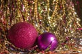 Two red Christmas balls on shiny tinsel. Two Christmas toys of the same color and different sizes. Royalty Free Stock Photo