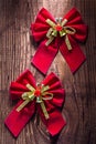 Two red christmas bows with gold ribbon and little bells on old Royalty Free Stock Photo