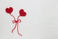 Two red crochet wool hearts and ribbon on white crochet background, love story. The concept for 14 February, romantic Valentine