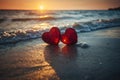 Two red crystal hearts lying on a sandy beach at sunset. Romantic wallpaper. Valentine\'s Day background.