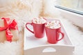 Two red cup of hot chocolate with marshmallow on white windowsill with furskin for rest. Holiday. Romantic. Royalty Free Stock Photo