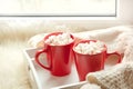 Two red cup of hot chocolate with marshmallow on white windowsill with furskin for rest. Holiday. Royalty Free Stock Photo