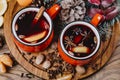 Two red cups of Christmas mulled red wine with spices, cinnamon stick, apples and citrus fruits orange, lemon on a rustic wooden Royalty Free Stock Photo