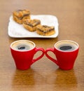 Two red cups of coffee and a plate with cakes Royalty Free Stock Photo