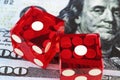 Two red dice lying side by side on blurry banknotes with Portrait of Benjamin Franklin, top view.