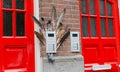 Two red doors on the facade of the house with birf feathers. Big street flowerpot with green plant. Amsterdam Oost. East side Royalty Free Stock Photo