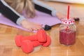 Two red dumbbell and smoothie in retro jar on floor and woman working stretching exercises Royalty Free Stock Photo