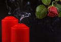 Two red extinguished candles with white smoke and withered rose flower on black Royalty Free Stock Photo