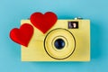 Two red fabric hearts and yellow vintage camera on blue backgrou Royalty Free Stock Photo