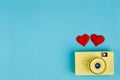 Two red fabric hearts and yellow vintage camera on blue backgrou Royalty Free Stock Photo