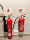 Two red fire extinguishers mounted on a white wall in an indoor setting. Royalty Free Stock Photo