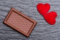 Two red fluffy hearts and a chocolate confection over rough black slate background
