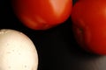 Two red fresh tomatoes. Mature. Dimmed light. On black background. Royalty Free Stock Photo