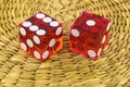 Two red glass dice on a wicker round rug.