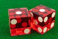 Two red glass professional dice on a green fleecy cloth. One and one macro photography