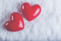 Two red glossy hearts on a frosty white snow background. Love and St. Valentine concept.