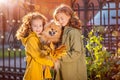 Two red-haired girls are walking down the street on a sunny autumn day. Walking with a small fluffy Pomeranian dog Royalty Free Stock Photo