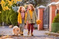 Two red-haired girls are walking down the street on a sunny autumn day. Walking with a small fluffy Pomeranian dog Royalty Free Stock Photo