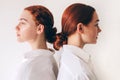 Two red-haired sisters stand isolated on a white background in shirts. Women standing with their backs to each other Royalty Free Stock Photo