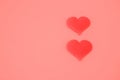 Two Red Heart cut outs on a pink background for Valentine's day