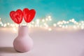 Two Red Heart Shape Candy Lollipops on Sticks in Vase Imitation of Flowers. Turquoise Background Valentine