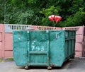 Two a red heart shaped balloons above a green dumpster Royalty Free Stock Photo