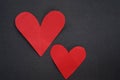 Two red hearts on black background. Paper love shaped on dark gray backgrounds. Red heart on backboard background