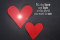 Be the love and light in the world you want to see. Two red hearts with light on gray background.