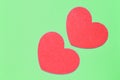 Two red hearts on a light green background closeup. Greeting card with copy space. Valentine`s Day concept Royalty Free Stock Photo