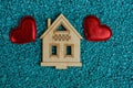 Two red hearts and a small house model on blue sand Royalty Free Stock Photo