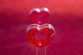 Two red hearts on a stand in the foreground on a red background with bokeh