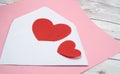 Two red hearts in a white envelope on a pink and wooden background, a copy of the space, the concept of Valentine's day Royalty Free Stock Photo