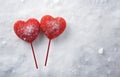 two red lollipops heart shape on grey snowy background top view Royalty Free Stock Photo