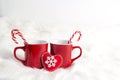 Two red mugs with candy cane on white fur background Royalty Free Stock Photo