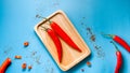 Two red peppers on a wooden tray on blue background