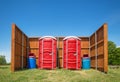 Two red portable restrooms in a park