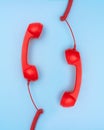 Two red telephones receiver hanging over blue background