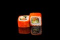 Two red tuna rolls with red caviar and shrimp on a black background with reflection. Close-up  top view. Food delivery concept Royalty Free Stock Photo