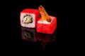 Two red tuna rolls with red caviar and shrimp on a black background with reflection. Close-up  top view. Food delivery concept Royalty Free Stock Photo