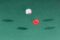 Two red and white dices falling on a green table Royalty Free Stock Photo